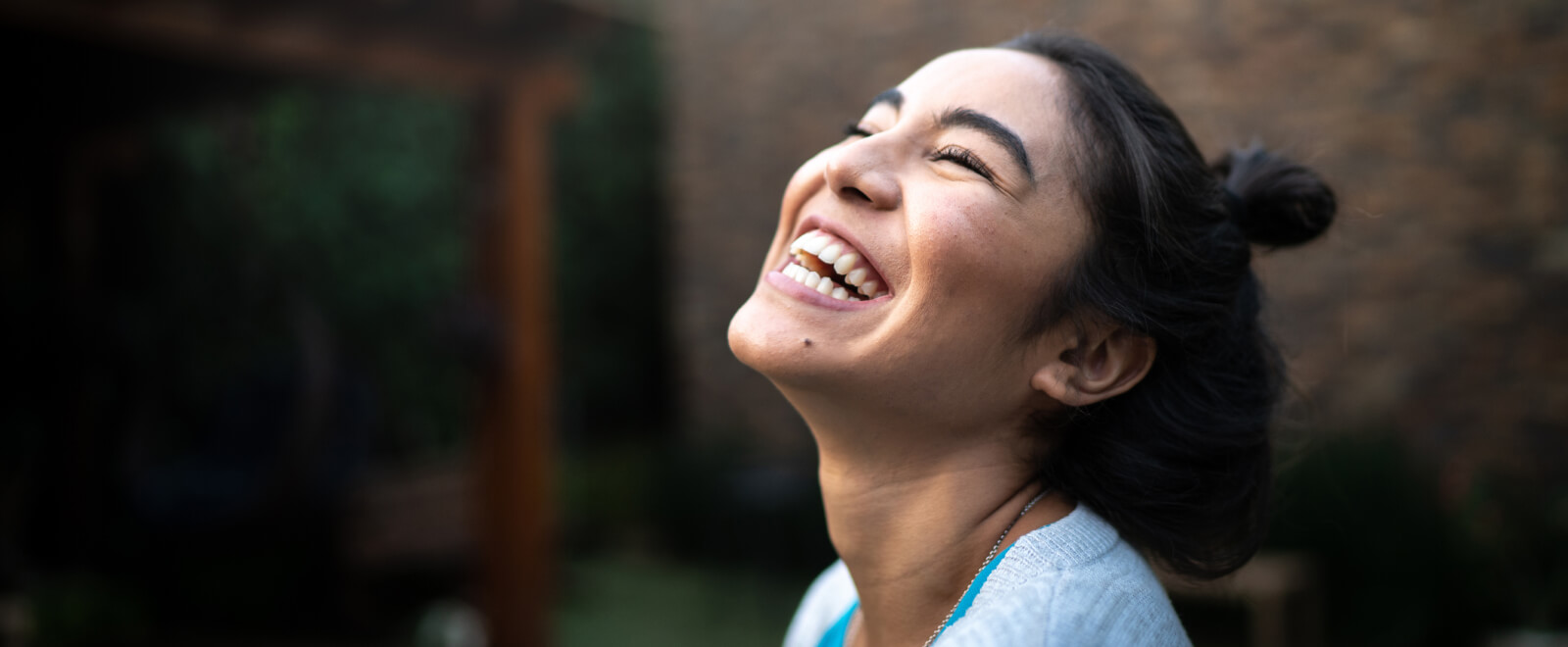 Young woman laughing outdoors.