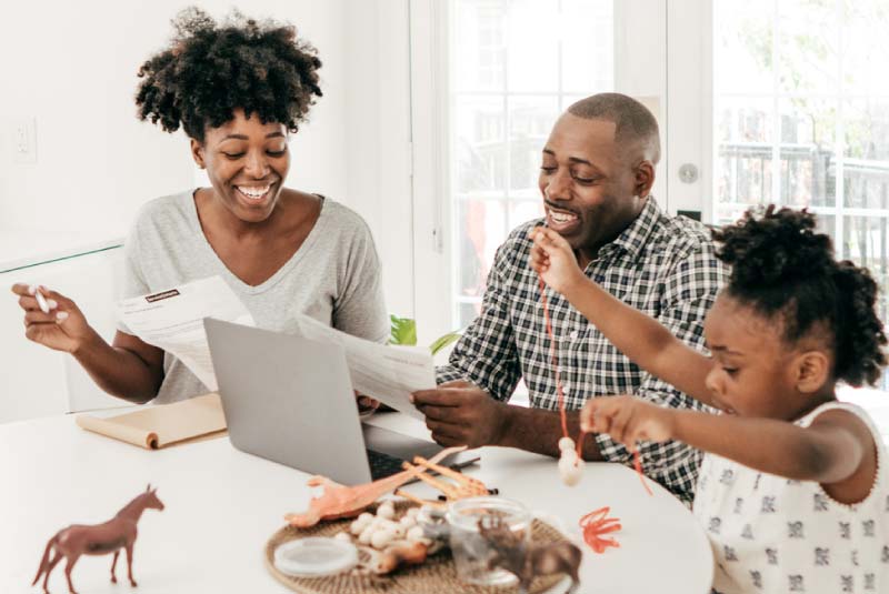 Happy family reviewing finances with a laptop, highlighting the stability and security of a Money Market Account for financial peace of mind.