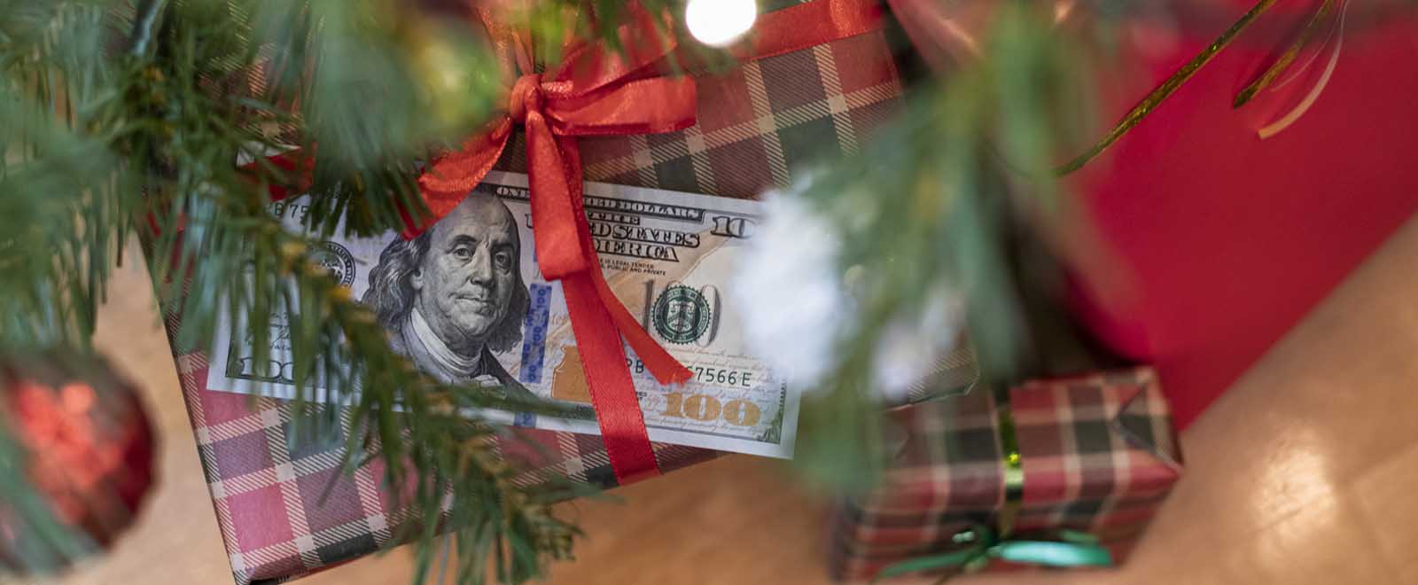 Gifts under a tree with cash, emphasizing the benefits of earning cash back during holiday shopping.