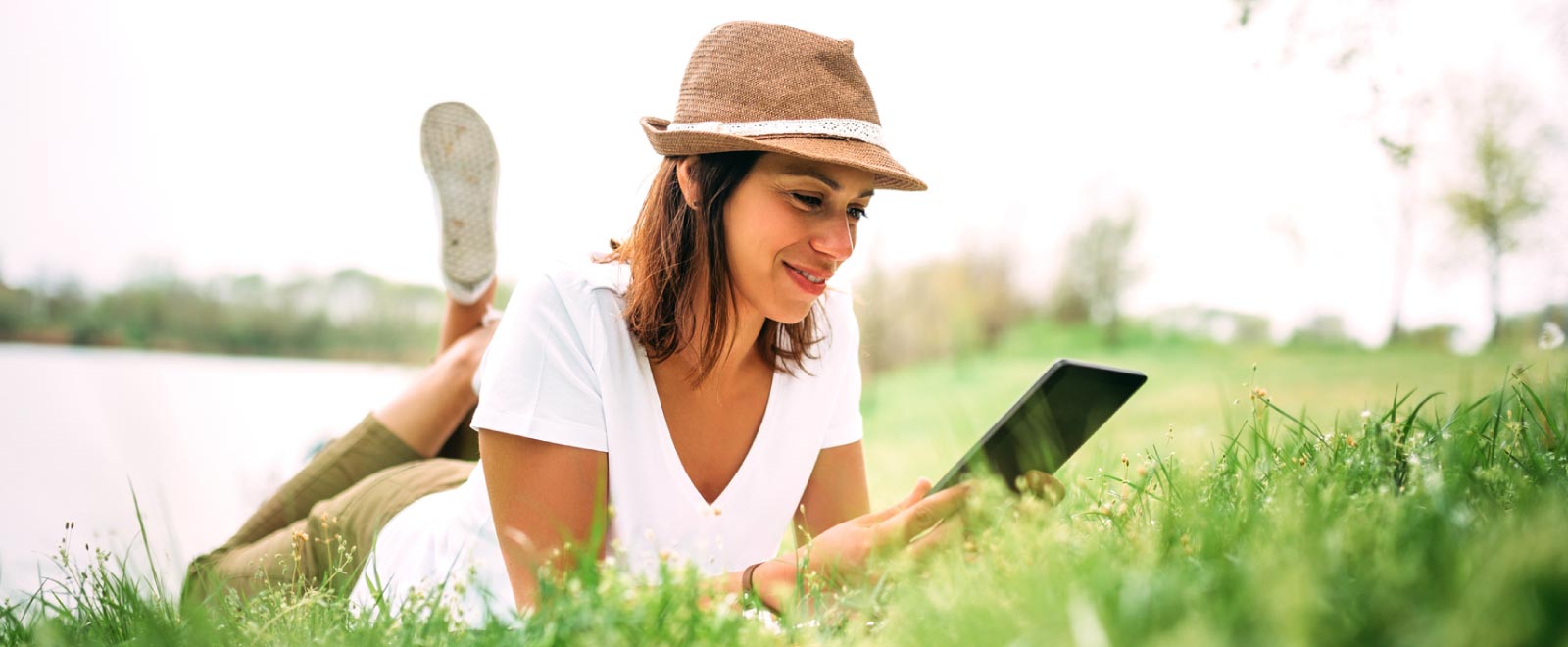 A woman relaxes outdoors while shopping online, enjoying the benefits of her Visa Platinum Rewards Credit Card.