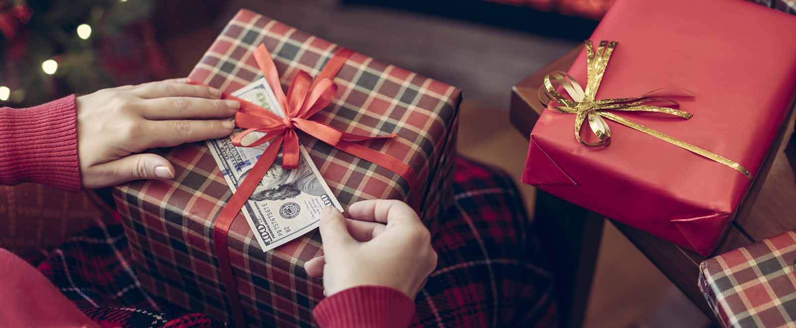 A person adding cash to gifts, emphasizing the benefits of earning cash back during holiday shopping.