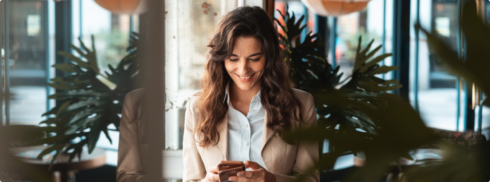 Woman in profession attire smiling while looking at smart phone