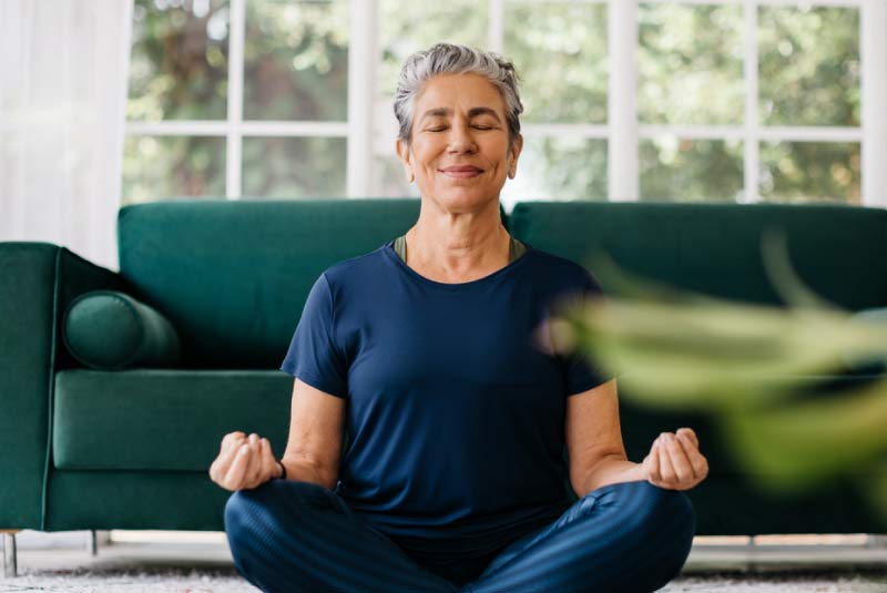 A woman meditating indoors, enjoying the financial peace of mind provided by a certificate